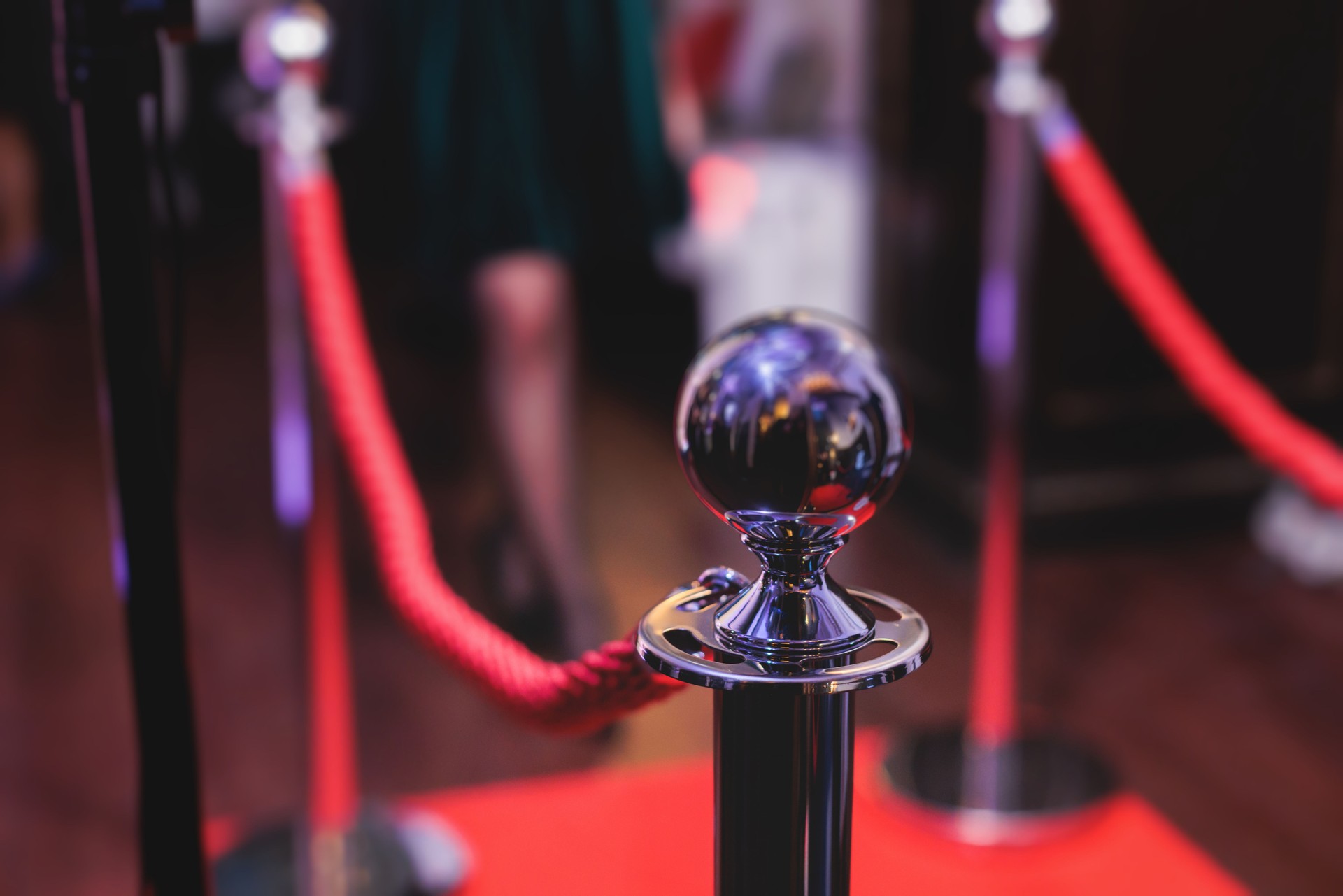 Red carpet with ropes and golden barriers on a luxury party entrance, cinema premiere film festival event award gala ceremony, wealthy rich guests arriving, outdoor decoration elements, summer day